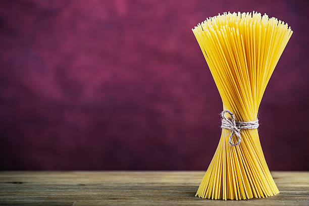 istock Bunch of spaghetti on wooden table -  purple background. 597939556