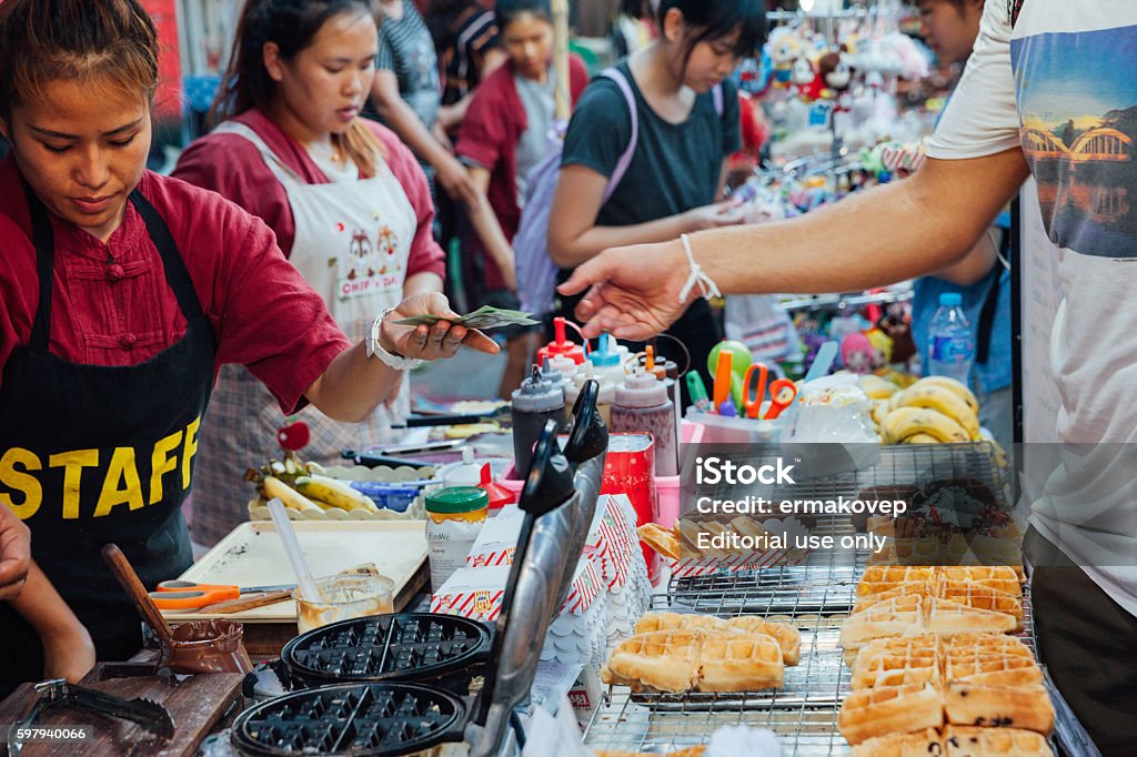 Woman cooks and sells waffles Chiang Mai, Thailand - August 21, 2016: Thai woman sells waffles at the Sunday Market (Walking Street). Market - Retail Space Stock Photo