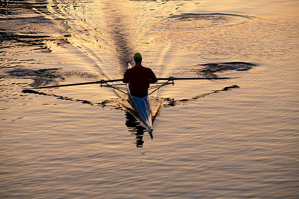 Galicia, Spain-Februrary, 29 2012: Individual single scull kayak rower with back turned rowing towards the camara. The elevated angle of view shows the late afternoon light and reflections are visible on the water surface.