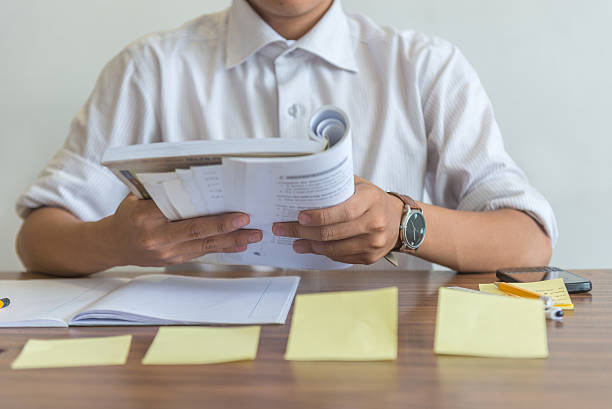istock Close-up of student hand holding book while reading it 597943840