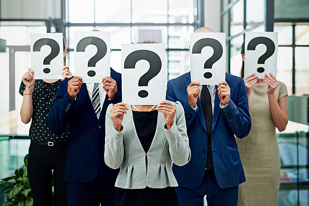 Who's in charge here? Cropped shot of a group of unidentifiable businesspeople holding placards with question marks on them in front of their faces unidentifiable persons stock pictures, royalty-free photos & images