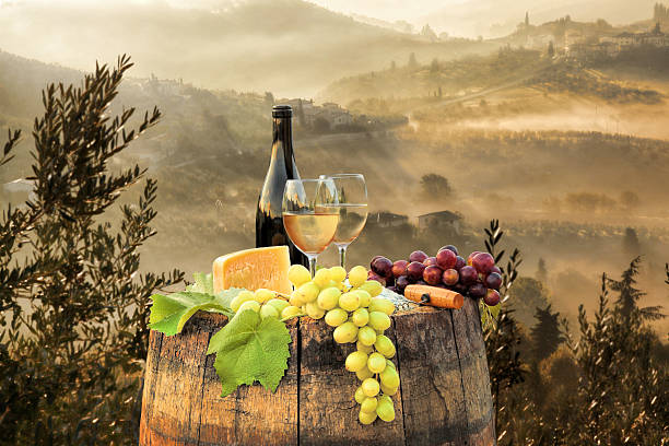 istock White wine with barrel on famous vineyard in Chianti, Italy 597946340