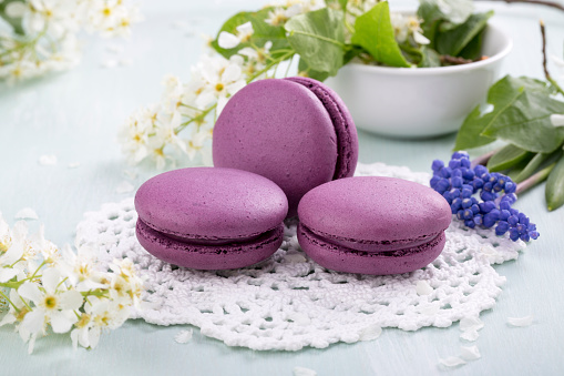 Three purple macaroons cookies and flowers on the table