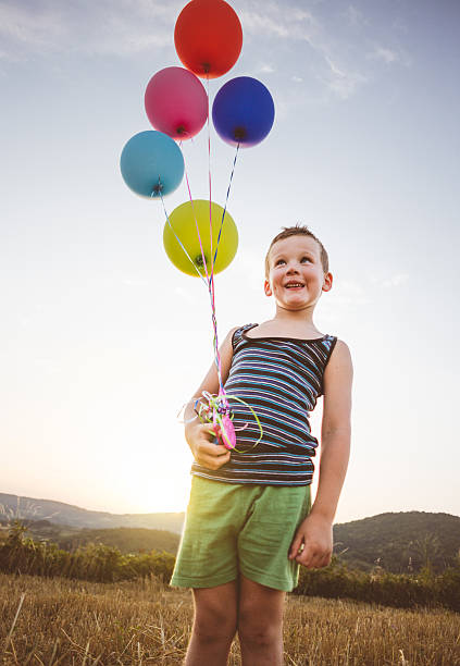 istock Gorgeous boy smiling and holding balloons joyfully 597947862