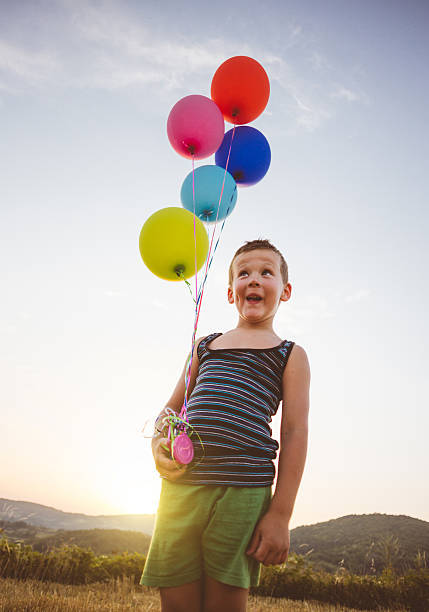 istock Humorous kid holding baloons in natural landscape 597947956