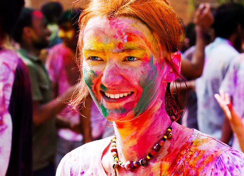 European girl celebrate festival Holi in Delhi, India. The main day, Holi, is celebrated by people throwing coloured powder and coloured water at each other.