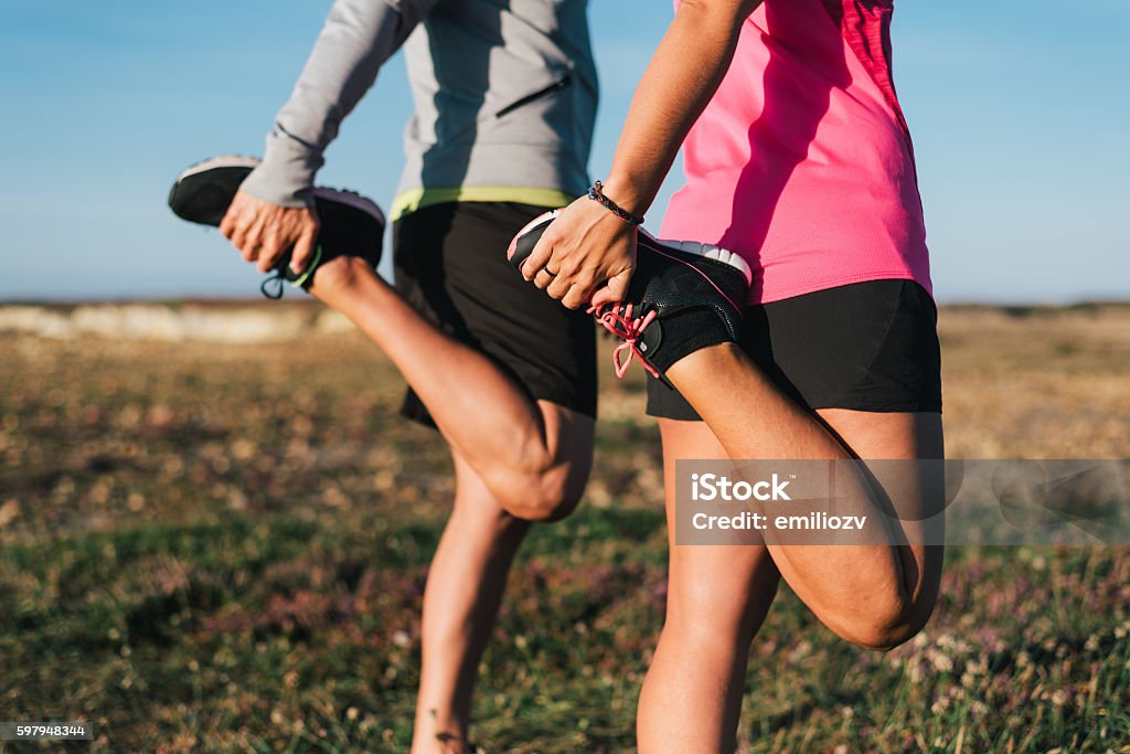 Sporty couple stretching legs outdoors before trail running workout outdoors Sporty couple stretching legs outdoors before trail running workout outdoors. Fitness healthy lifestyle concept. Stretching Stock Photo