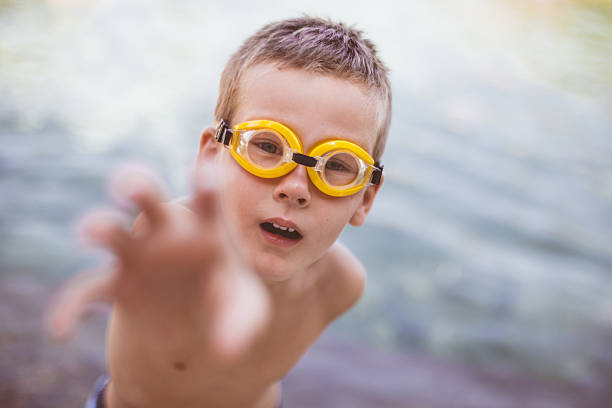Curious blond boy in swim goggles is reaching for something interesting