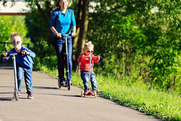 istock mother with kids riding scooters in summer 597951168