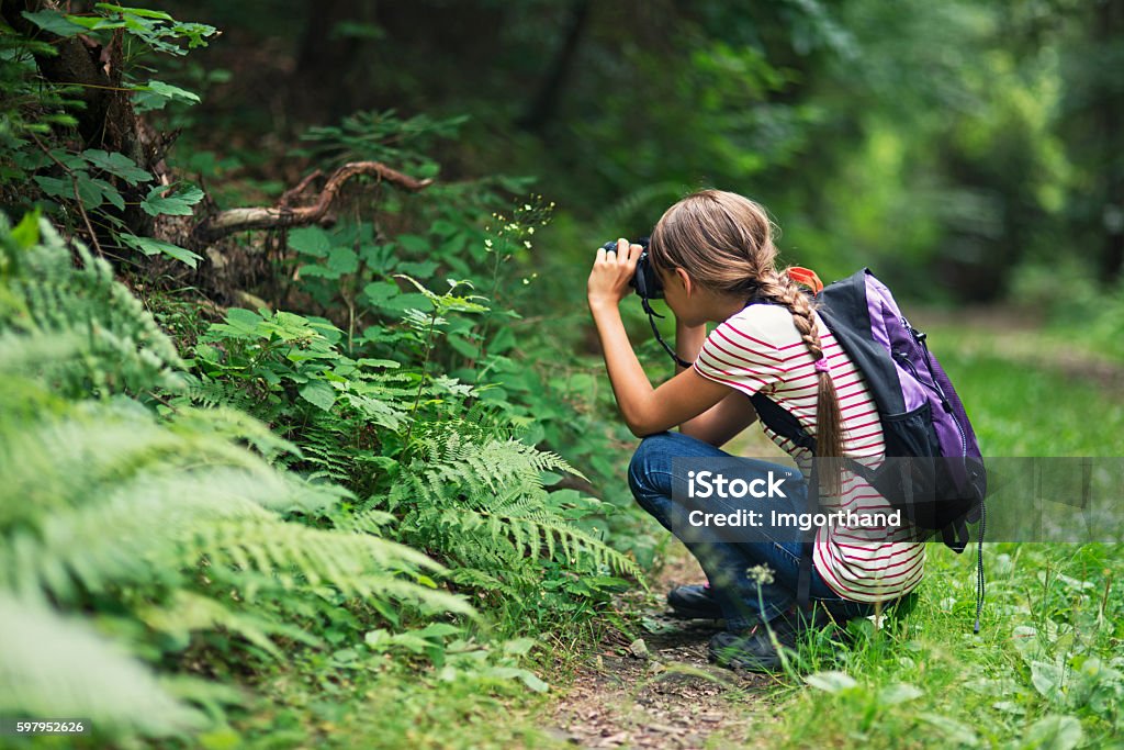 Little girl taking photos in the forest Little girl taking photos in the forest. The girl is aged 10 and is wearing backpack. Child Stock Photo