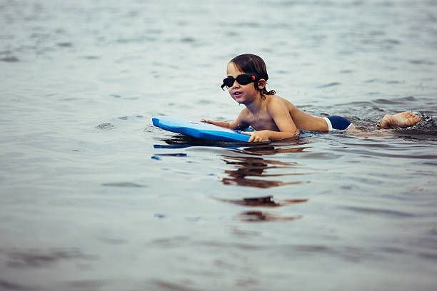 istock Smiling boy on bodyboard in water 597952952