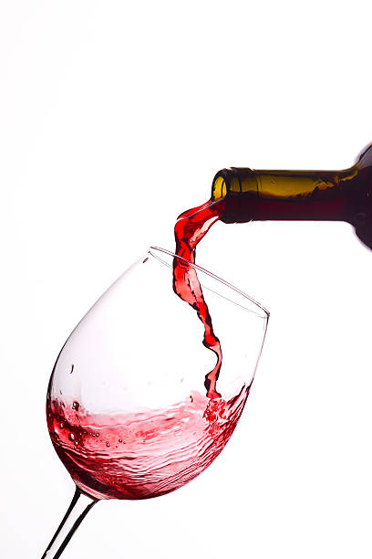 Pouring red wine from a bottle Pouring red wine into a glass, isolated on white background. winetasting rose wine wineglass elegance stock pictures, royalty-free photos & images