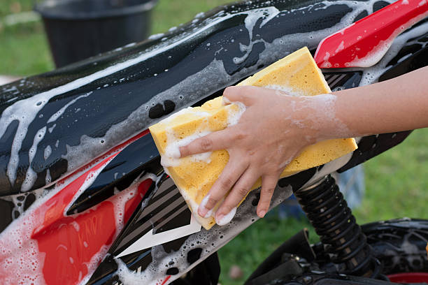 istock Female hand with  yellow sponge  washing a motorcycle. 597953870