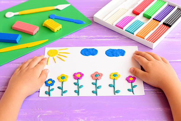 istock Child shows card with plasticine flowers, sun and clouds 597953954