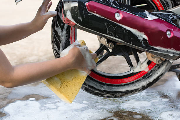 istock Female hand with  yellow sponge  washing a motorcycle. 597954008