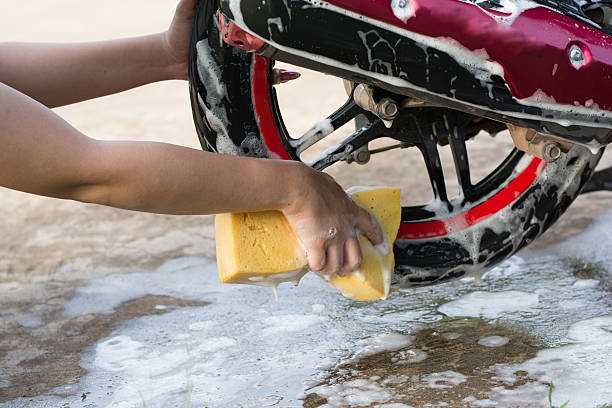 istock Female hand with  yellow sponge  washing a motorcycle. 597954106