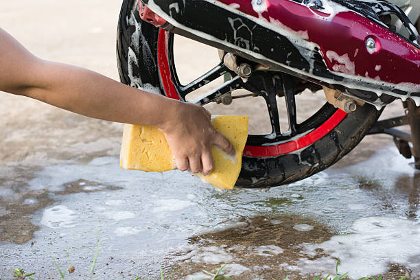 istock Female hand with  yellow sponge  washing a motorcycle. 597954272