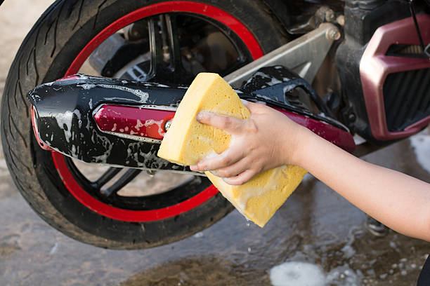 istock Female hand with  yellow sponge  washing a motorcycle. 597954434