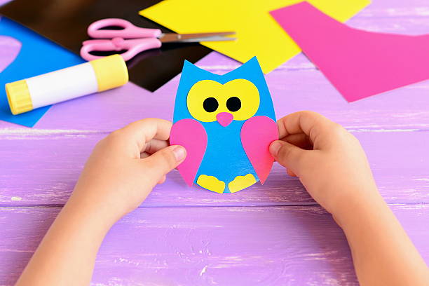 istock Small child holds paper owl in his hands 597954786