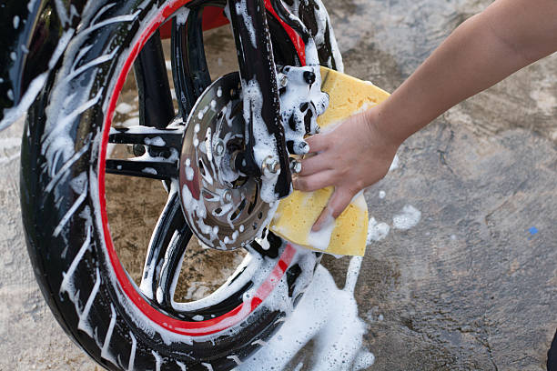 istock Female hand with  yellow sponge  washing a motorcycle. 597954964