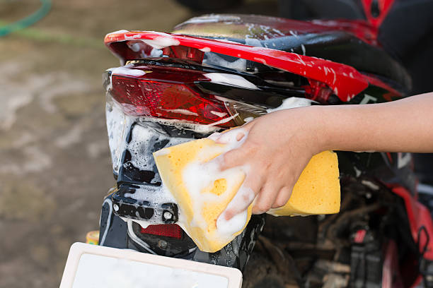 istock Female hand with  yellow sponge  washing a motorcycle. 597955310