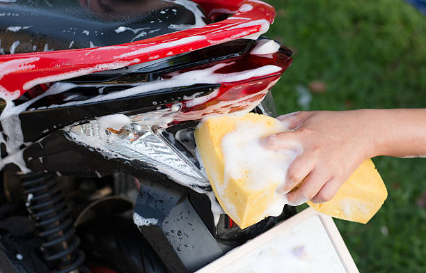 istock Female hand with  yellow sponge  washing a motorcycle. 597955378
