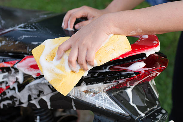 istock Female hand with  yellow sponge  washing a motorcycle. 597955452