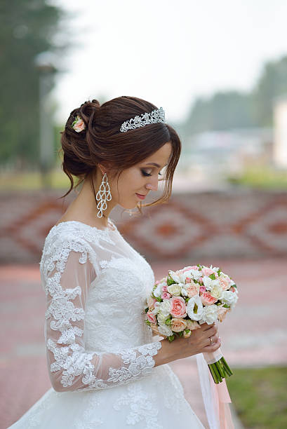 istock Young beautiful happy bride with flower bouquet in park 597957214