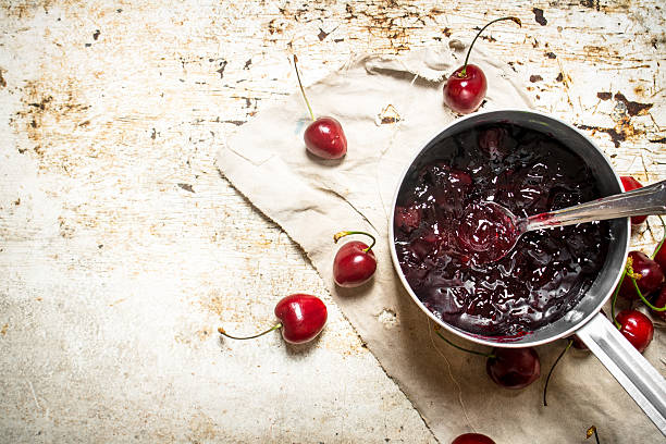 istock Cherry jam in a saucepan on the old fabric. 597957634