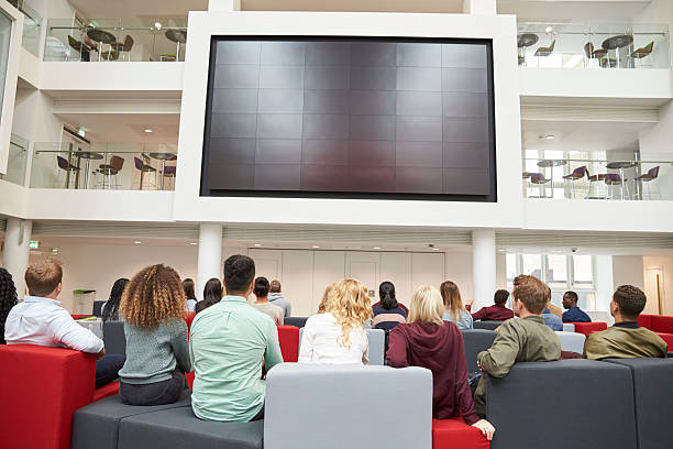 studenti che guardano il grande schermo nell'atrio universitario, vista sul retro - lecture hall college student university multi ethnic group foto e immagini stock