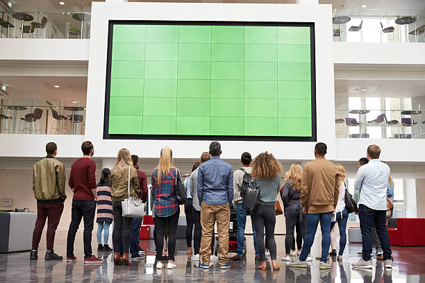 des étudiants regardant un grand écran dans un bâtiment universitaire - atrium élément architectural photos et images de collection