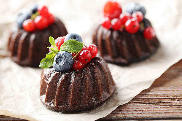 istock Sweet chocolate cakes with berries on wooden table 597958542