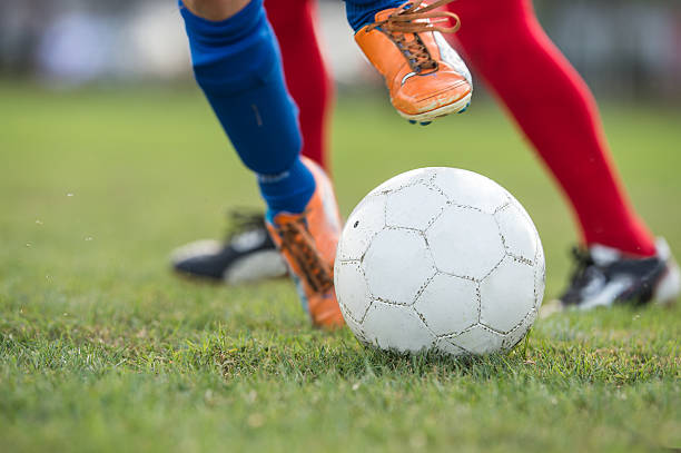 istock Foot kicking soccer ball on the field 597958556