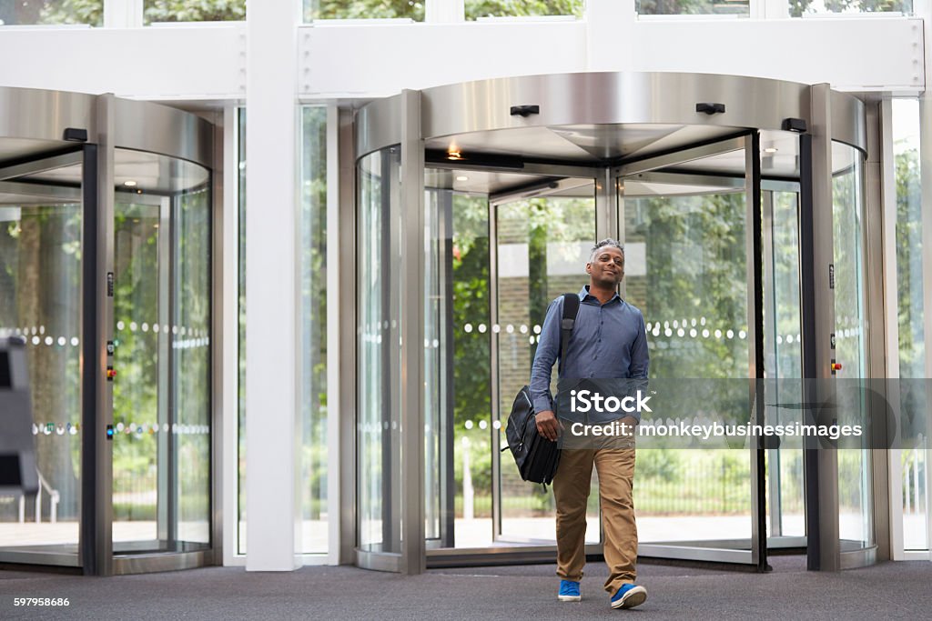 Hombre negro de mediana edad entrando en el vestíbulo del edificio moderno - Foto de stock de Llegada libre de derechos