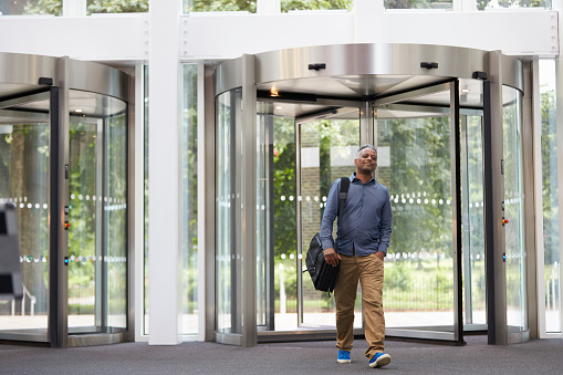 Middle aged black man entering the foyer of modern building