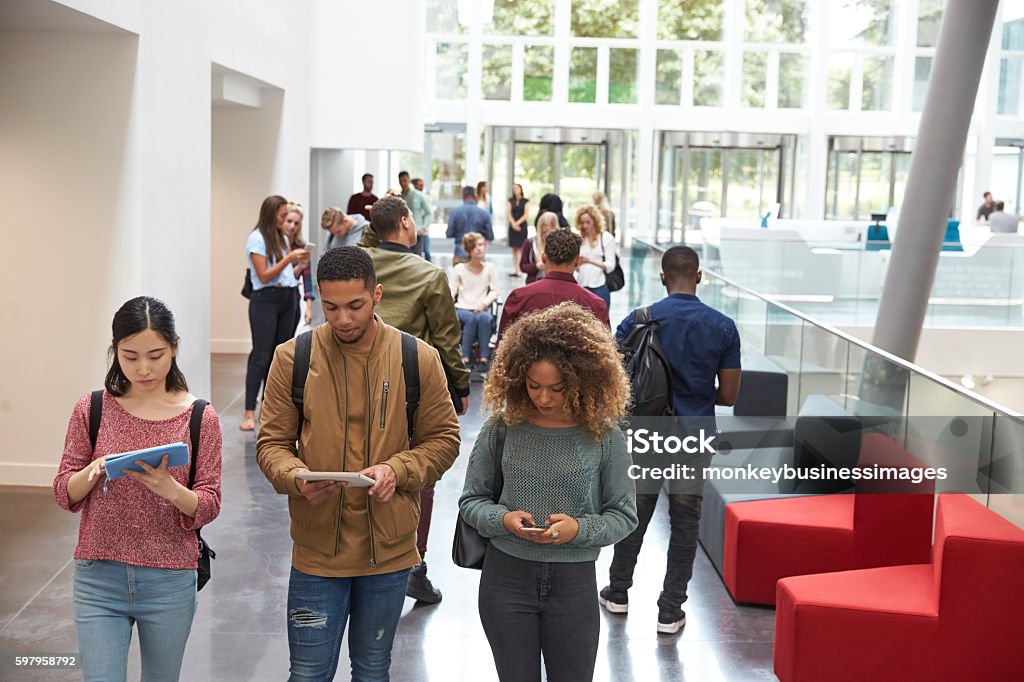 Students walk in university campus using tablets and phone Campus Stock Photo