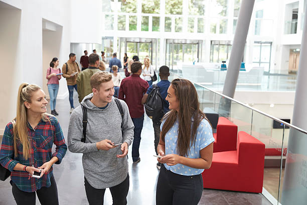 istock Students holding tablets and phone talk in university lobby 597958816