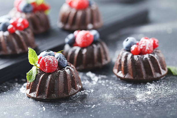 istock Sweet chocolate cakes with berries on black wooden table 597958996