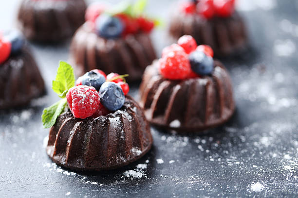 istock Sweet chocolate cakes with berries on black wooden table 597959088