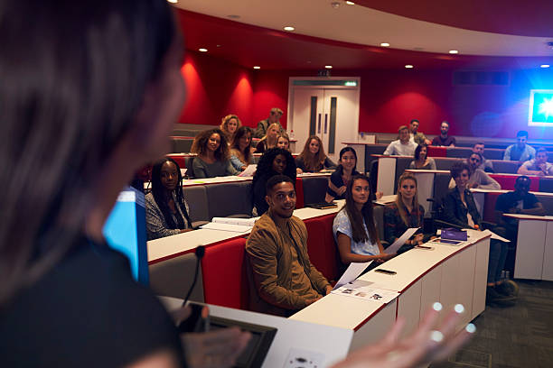 istock Woman lecturing students in lecture theatre, focus midground 597959094