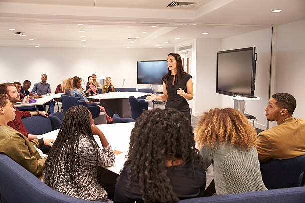 Female teacher addressing university students in a classroom Female teacher addressing university students in a classroom classroom stock pictures, royalty-free photos & images