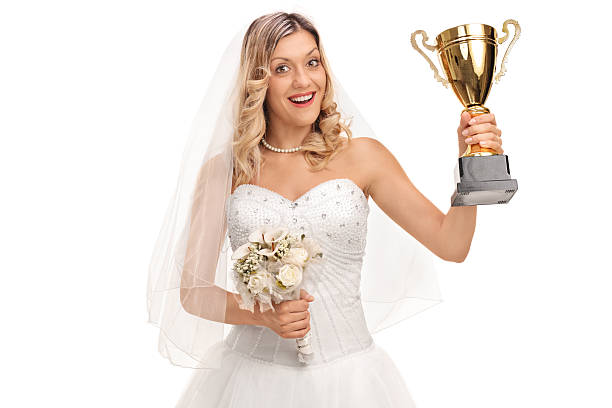 Bride holding a trophy Cheerful bride holding a bouquet of flowers and a trophy isolated on white background trophy wife stock pictures, royalty-free photos & images