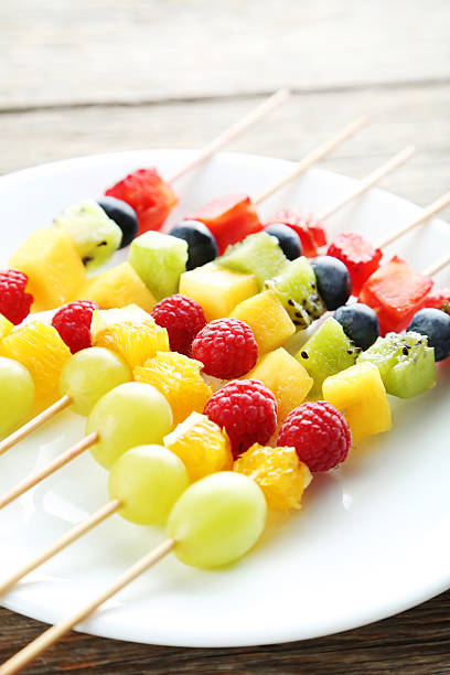 istock Fresh fruit on skewers on a grey wooden table 597960450