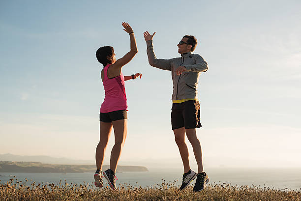 istock Fitness running couple giving five while jumping outdoor 597960576