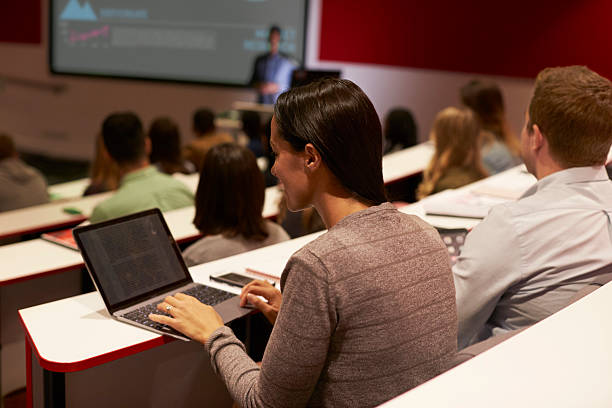 adult student using laptop computer at a university lecture - lecture hall university student seminar imagens e fotografias de stock