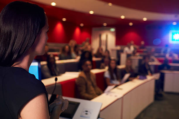 istock Woman lecturing students in lecture theatre, focus foreground 597963340