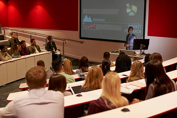 Young adult students at a university lecture, back view Young adult students at a university lecture, back view lecture hall stock pictures, royalty-free photos & images