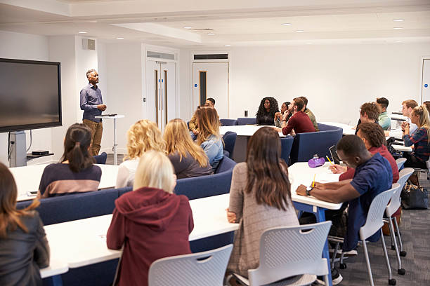 University students study in a classroom with male lecturer University students study in a classroom with male lecturer classrooms stock pictures, royalty-free photos & images