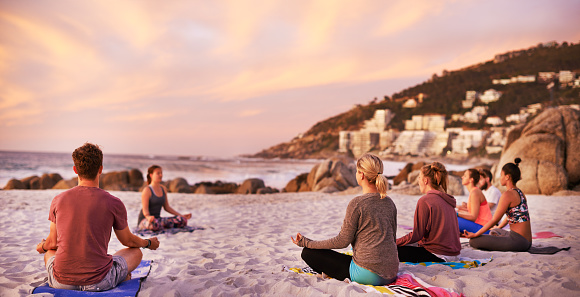 Shot of a group of people having a yoga session on the beach