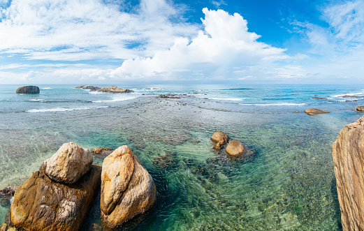 Indian ocean , Sri Lanka. Shot taken at Galle Fort. Turquoise ocean and rocks in the centre of composition. Clear blue sky with few low clouds on the background. Shot with Canon 5D mk III